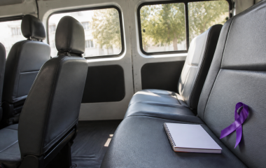 Conceptual empty minibus taxi interior with a purple awareness ribbon and notebook