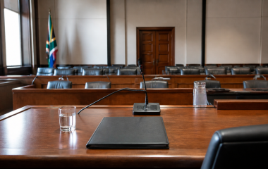 Empty inquiry hearing room with a witness microphone and closed folder