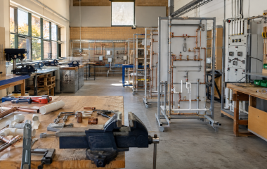 An empty vocational workshop equipped with plumbing rigs and hand tools