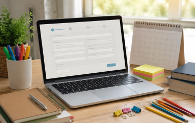 Laptop displaying a generic enrolment form beside school stationery