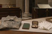 A patterned shirt, closed green document and hearing-aid case on a museum conservation table