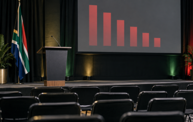 Empty conference lectern and chairs before an abstract declining bar chart