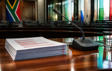 Illustration of a draft report and microphone in a parliamentary committee room