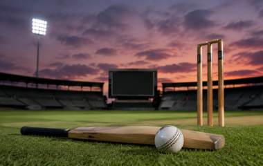 Cricket bat, ball and stumps on an empty floodlit ground