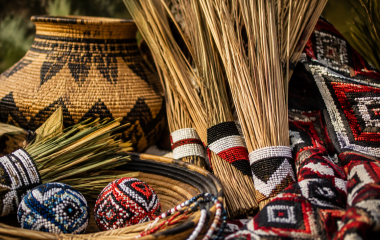 Reeds, woven baskets and beadwork-inspired textiles arranged in warm light