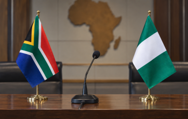 South African and Nigerian flags beside an empty briefing-room microphone