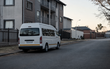 An unbranded scholar transport minibus parked on a quiet Johannesburg street