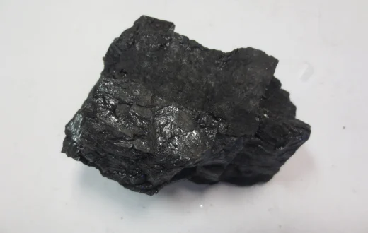A bituminous coal sample on a pale background.