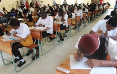 Learners seated at individual desks writing examinations.
