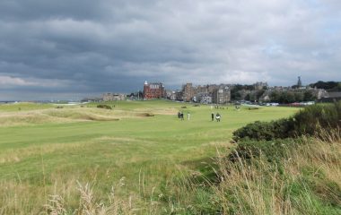 Archive view of the Old Course at St Andrews, with golfers and town buildings in the background