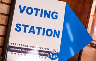 An Electoral Commission sign reading “Voting Station” with a blue arrow pointing right.