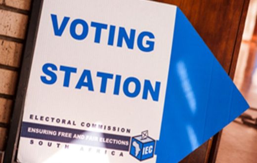 An Electoral Commission sign reading “Voting Station” with a blue arrow pointing right.
